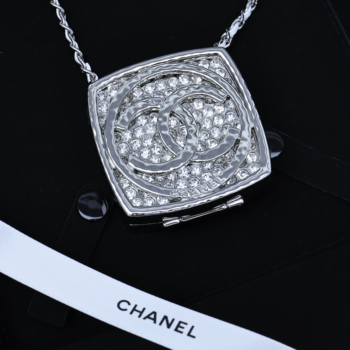 Silver-tone rhinestone square pendant necklace with ornate circular emblem