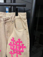 Beige denim pants with large pink cross embroidery on thigh