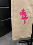 Beige denim pants with small pink cross embroidery on leg