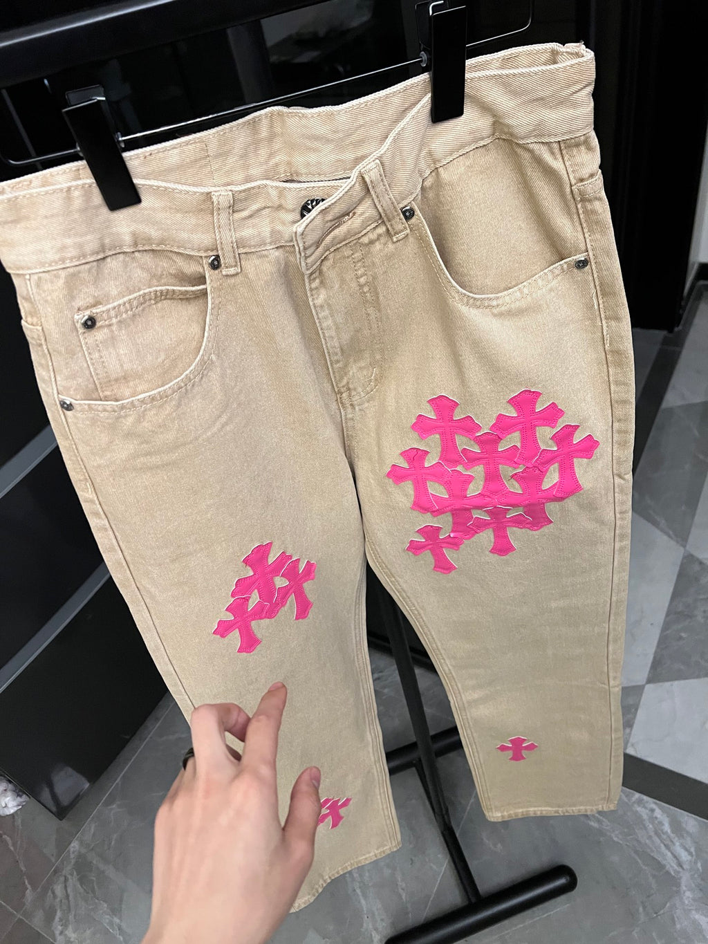 Beige denim pants with pink cross embroidery on front and side