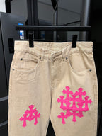 Beige denim pants with pink cross embroidery on front leg
