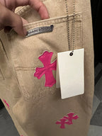 Beige denim pants with pink cross embroidery and attached size tag