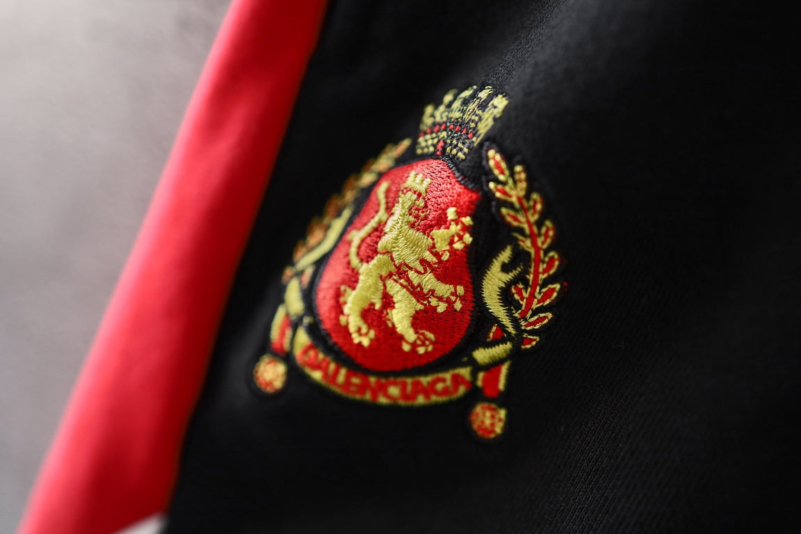 Black pants with an embroidered crest patch on the red side stripe