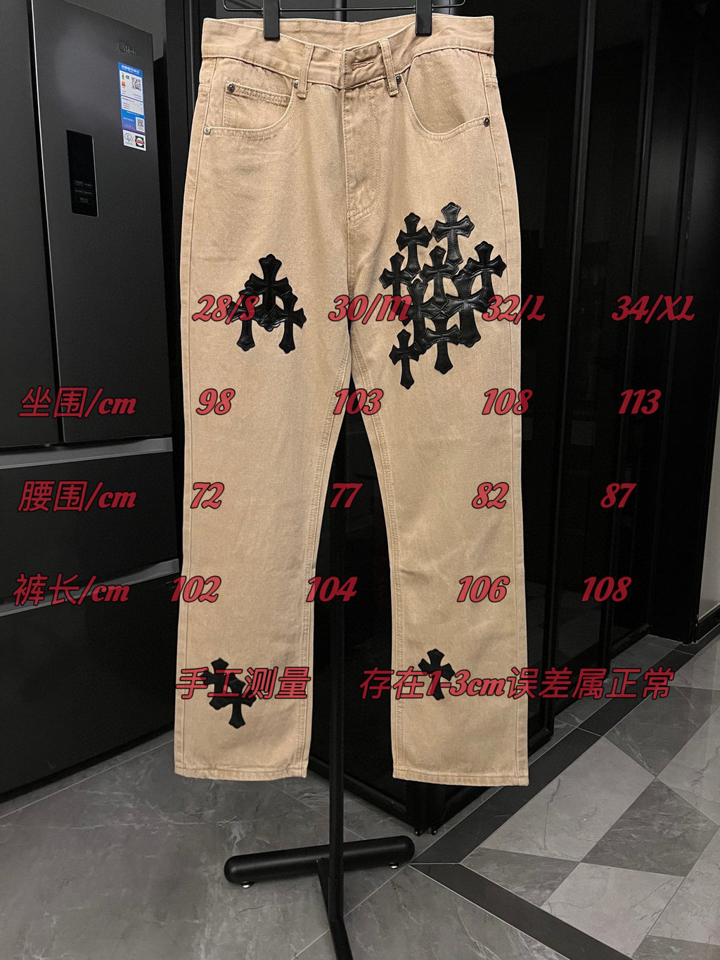 Beige denim pants with black cross patches and size measurement markings