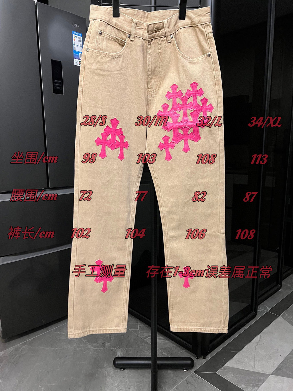Beige denim pants with pink cross embroidery and red size measurement markings
