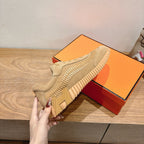 Beige Hermes unisex sneakers on orange box, lace-up with textured side stripes