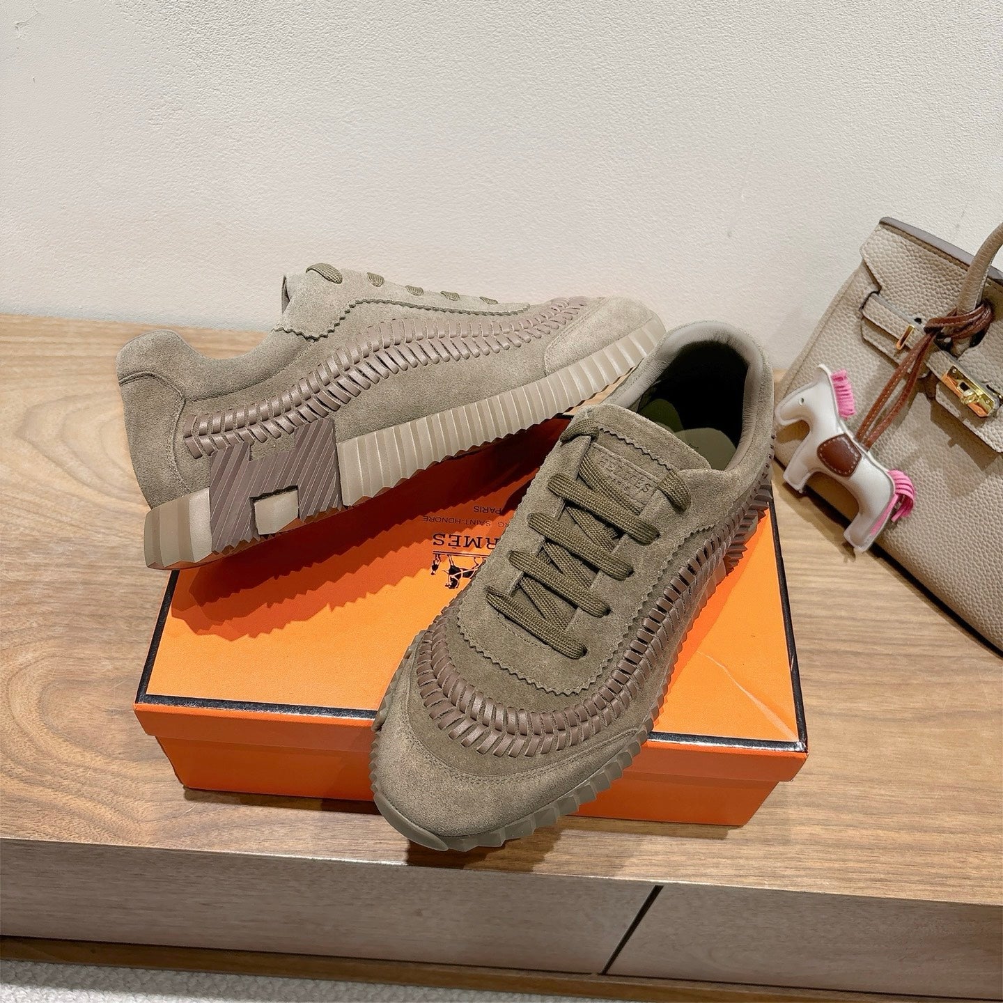 Olive suede lace-up sneakers with thick tread sole on orange shoebox