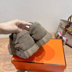 Olive suede sneakers being held with thick sole on orange shoebox