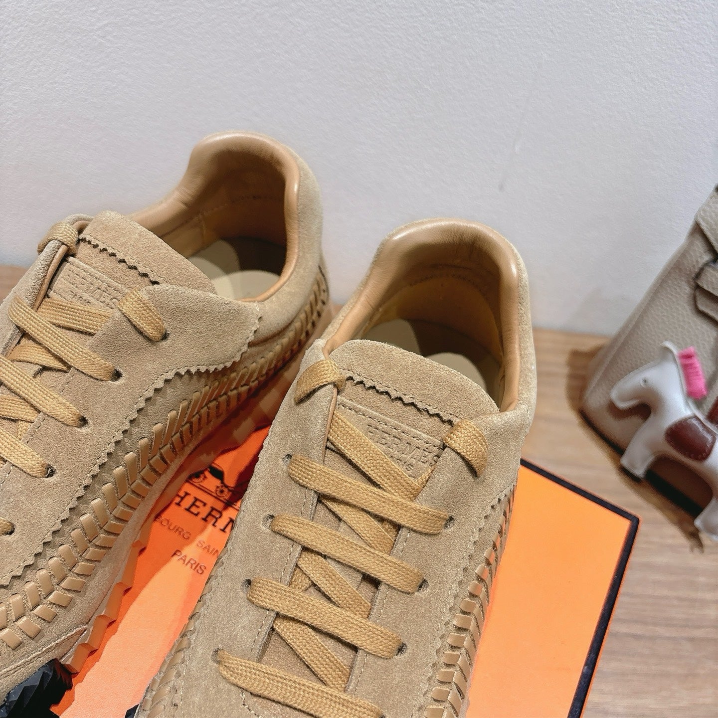 Beige Hermes unisex sneakers close-up, lace-up vamp with stitched side logo