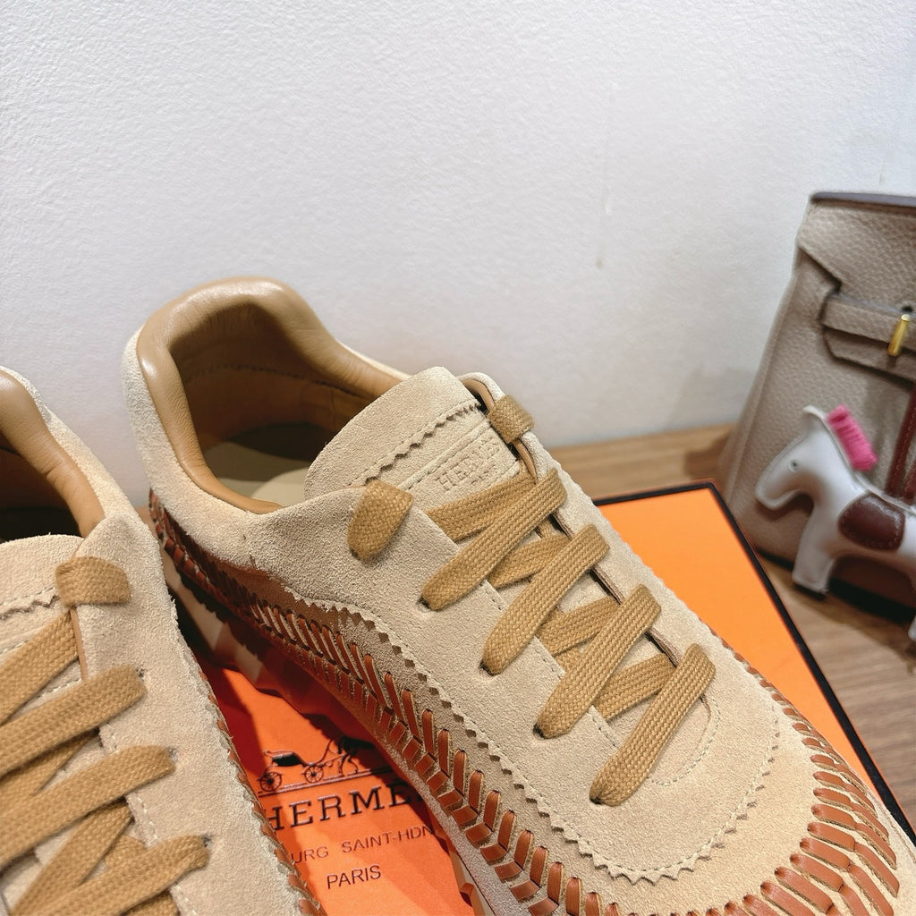 Unisex suede sneakers with beige upper, tan laces, and orange stitched side design