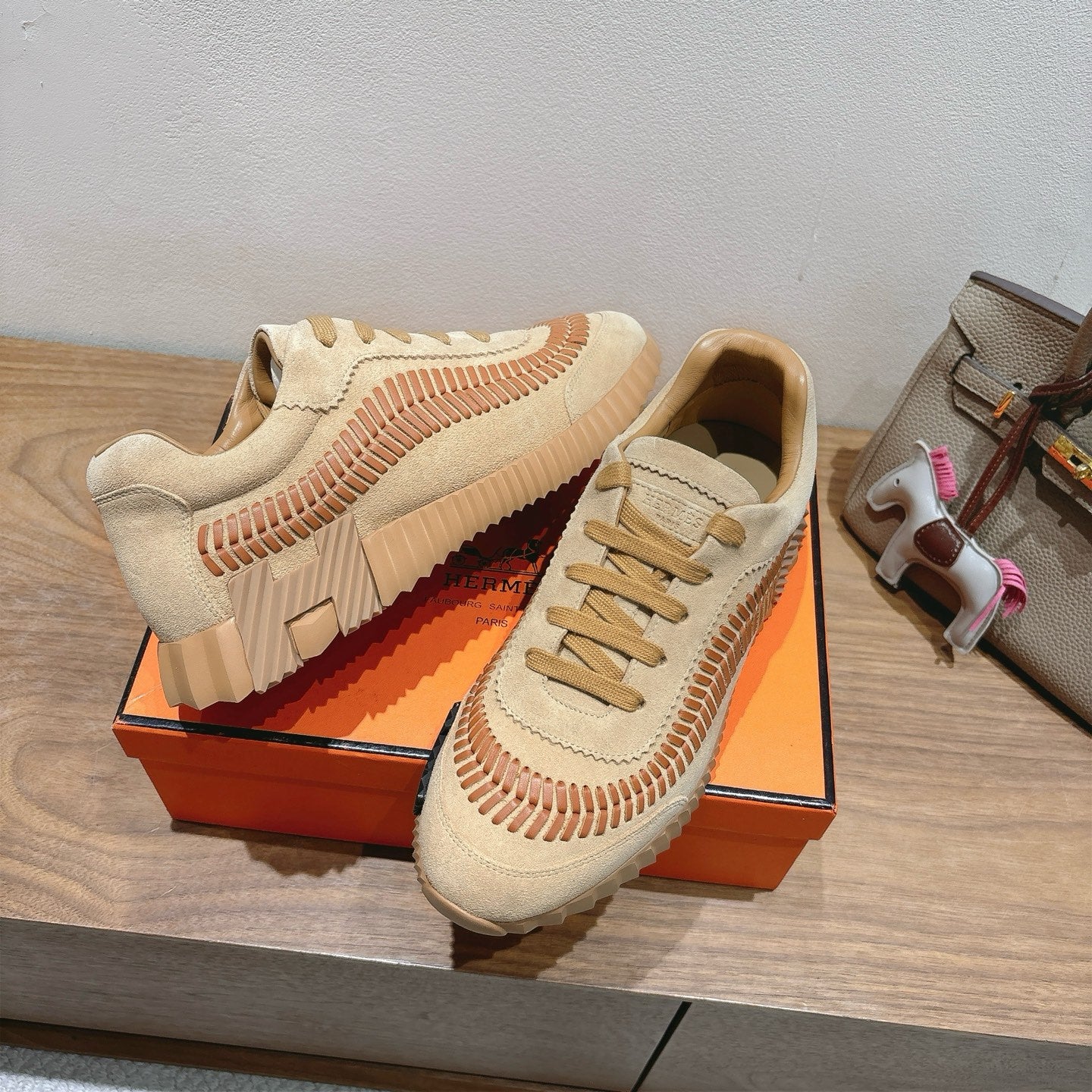 Unisex suede sneakers in beige with tan laces, orange stitch trim, and ribbed tread