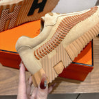 Unisex suede sneaker outsole view with orange stitch detail and ribbed traction tread