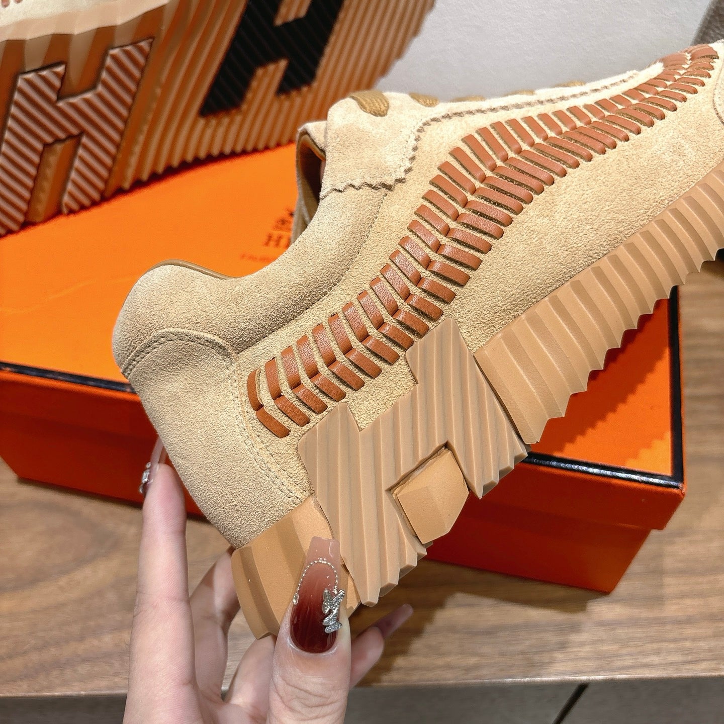 Unisex suede sneaker outsole view with orange stitch detail and ribbed traction tread