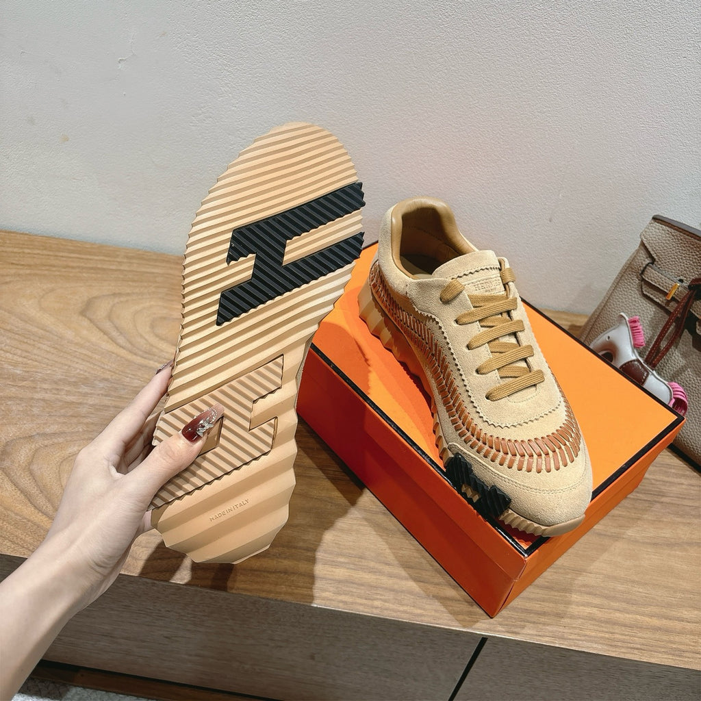 Unisex suede sneakers with tan laces, orange stitch line, and ribbed light sole
