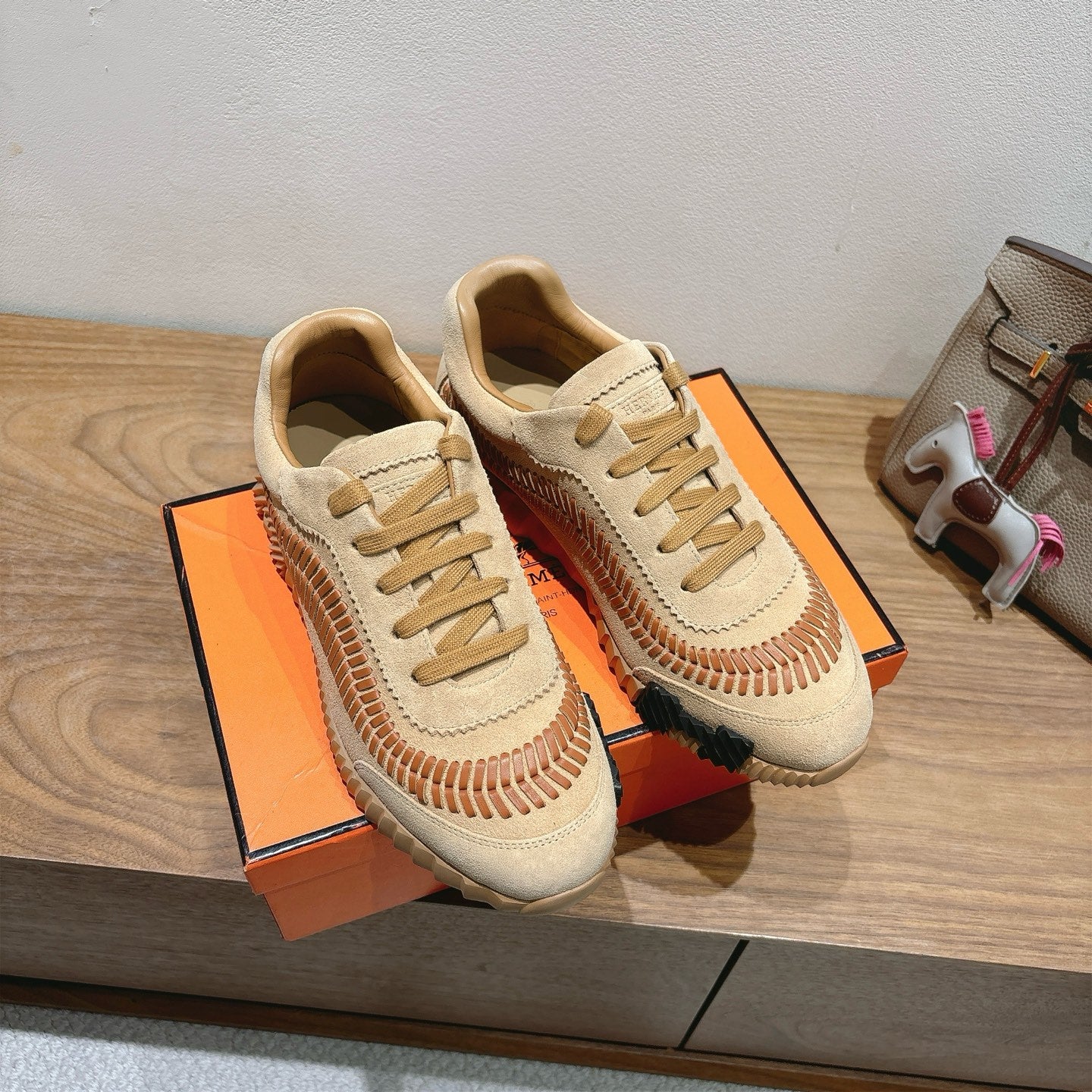 Unisex suede sneakers with tan laces, orange stitched seams, and thick rubber sole