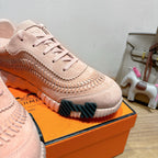 Hermes light pink suede sneaker close-up with lace-up eyelets and ridged side panel