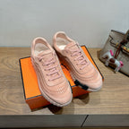 Hermes light pink lace-up sneakers resting on orange shoebox with suede overlays