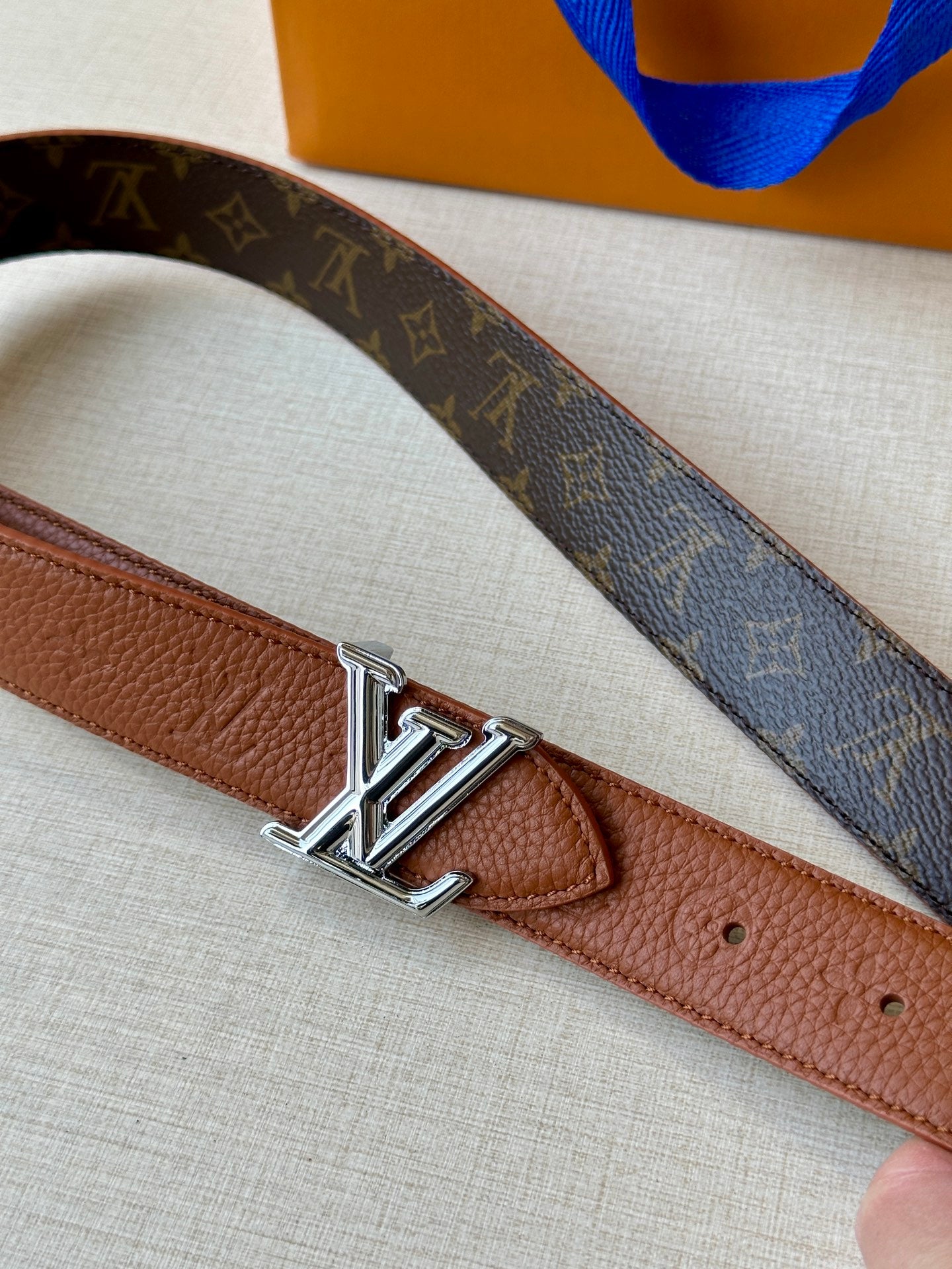 Louis Vuitton belt close-up: brown leather strap with LV silver-tone buckle.