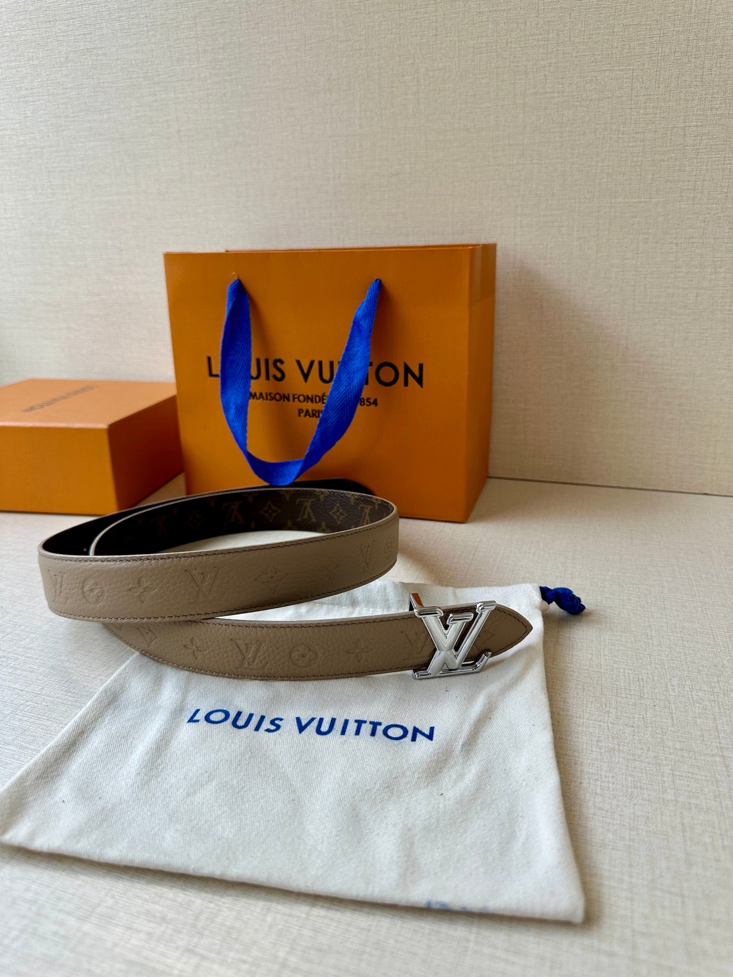 Beige monogram belt with gold-tone LV buckle laid flat