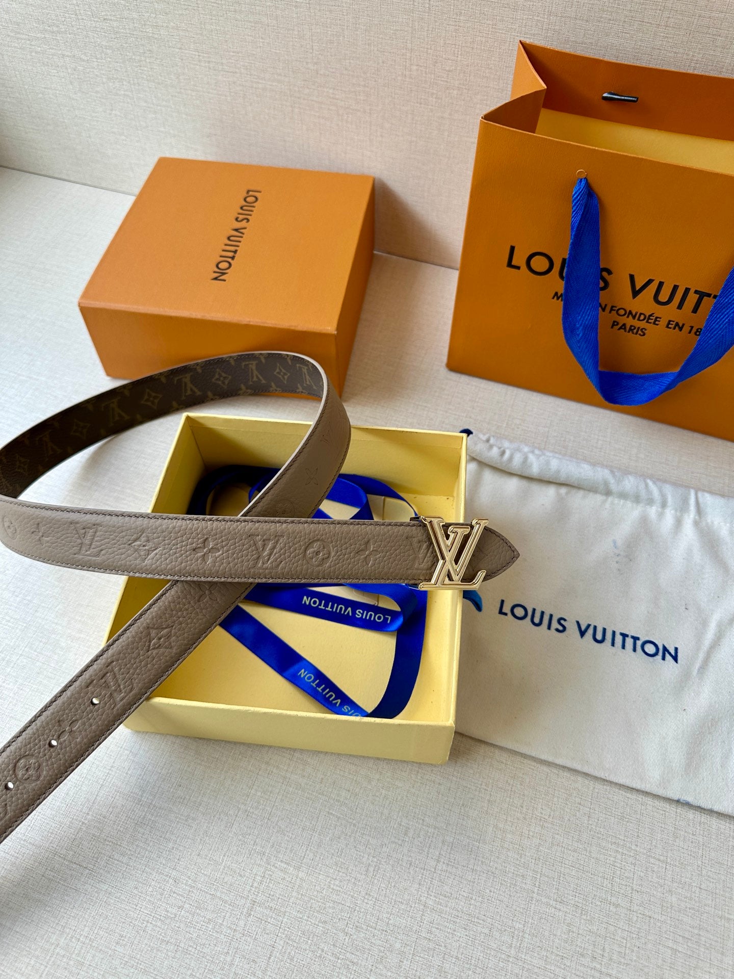 Beige monogram belt with gold-tone LV buckle and visible hole section