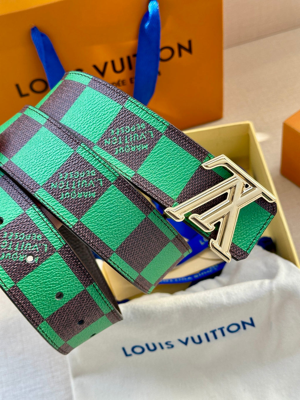Louis Vuitton belt with green check strap and silver LV buckle, angled view