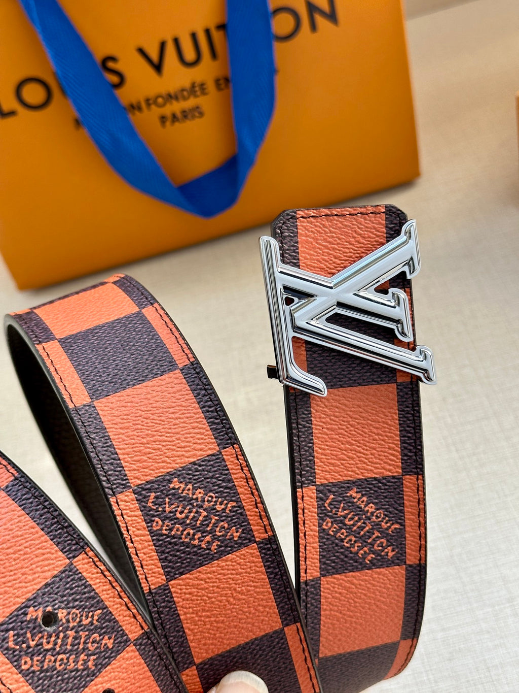 Orange and navy check belt with large silver buckle and strap end