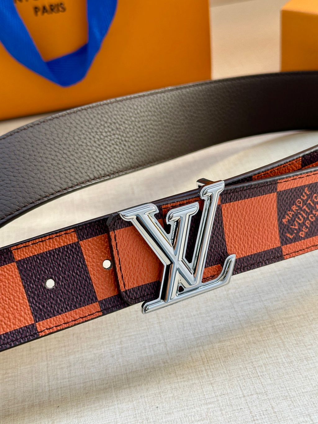 Close-up of orange and navy checker belt with silver buckle
