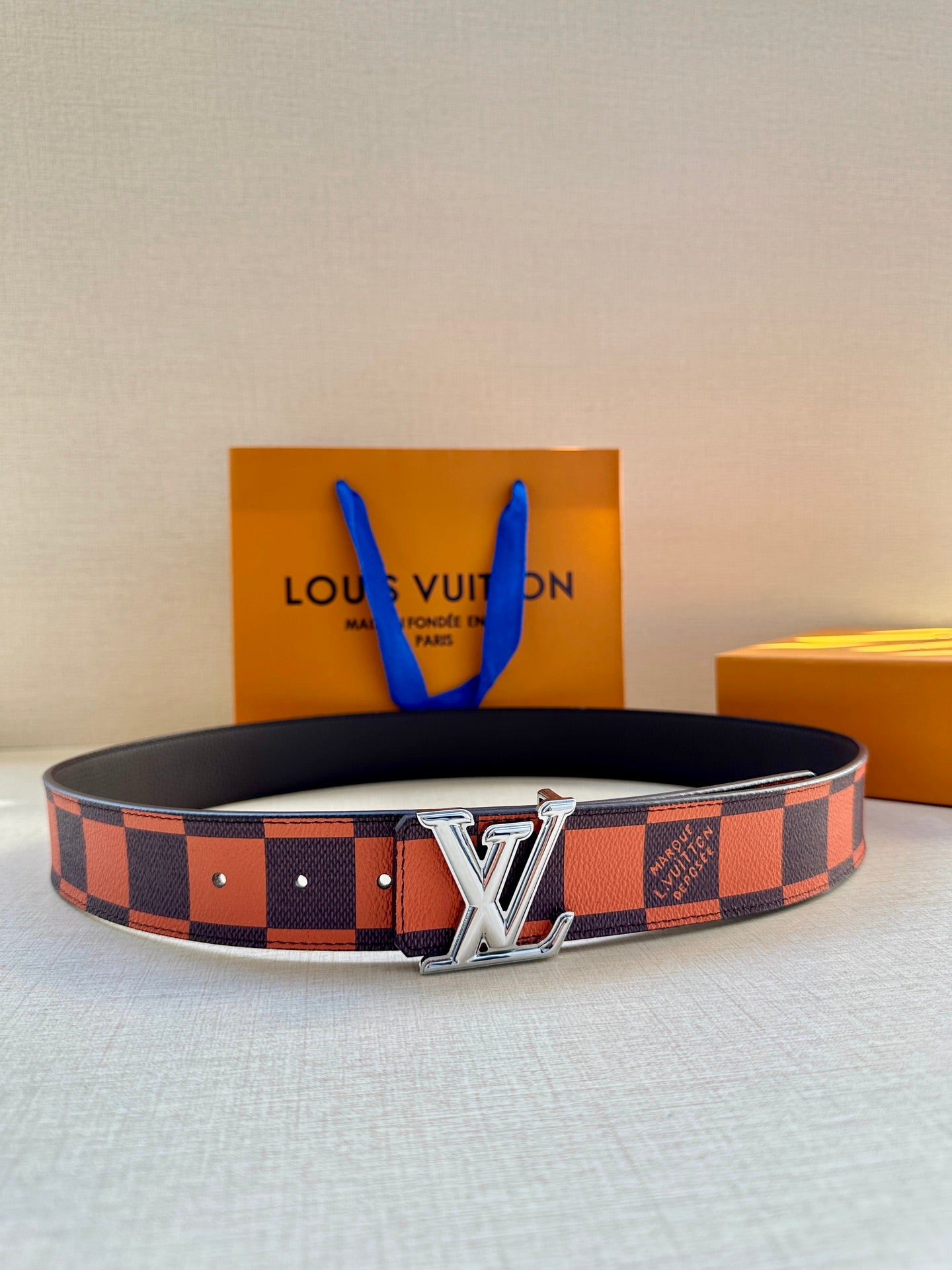 Orange and navy checker-print belt with silver LV-style buckle