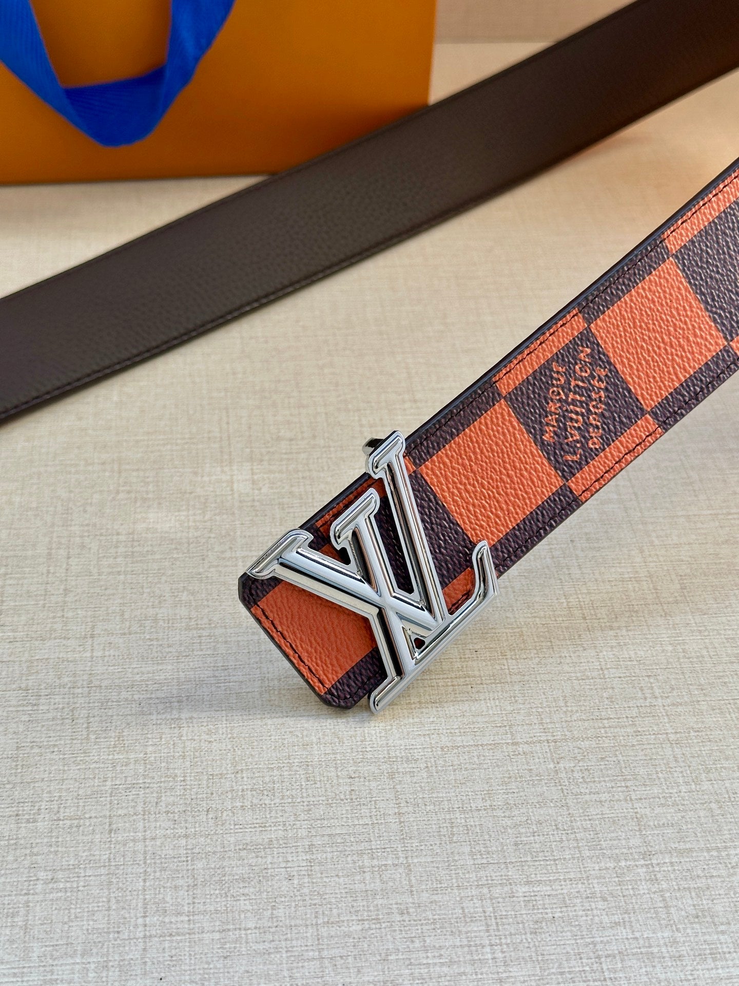 Orange and navy checker belt with silver buckle on dark leather strap