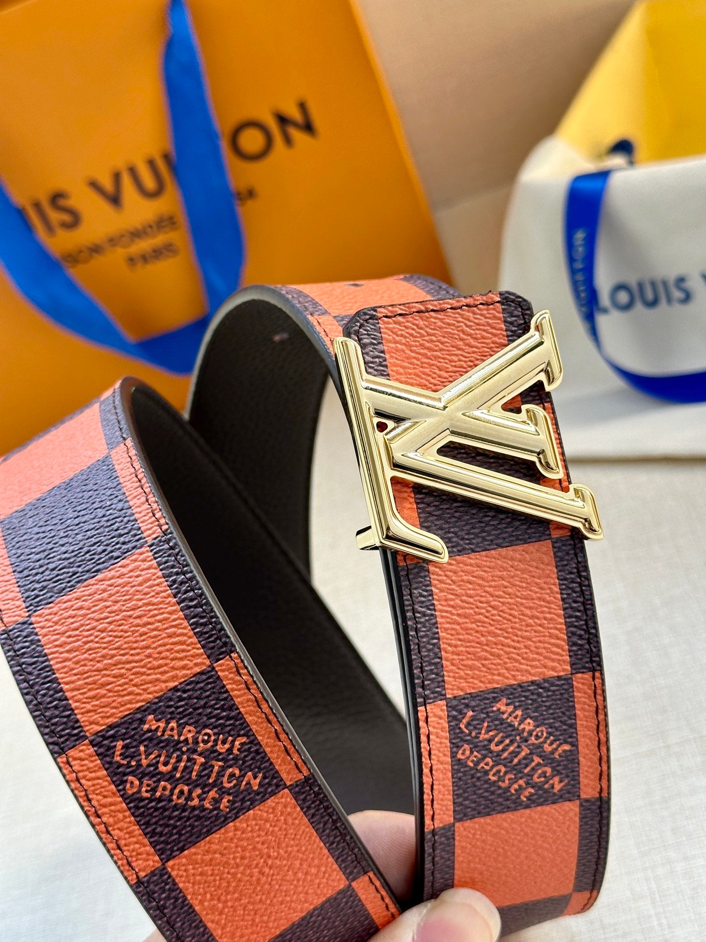Orange and navy checker belt with silver buckle over black inner strap