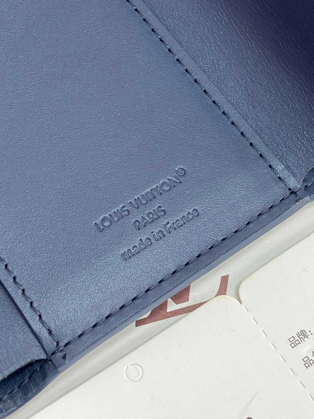 Blue leather card holder panel with 'Louis Vuitton Paris' embossing, stitched