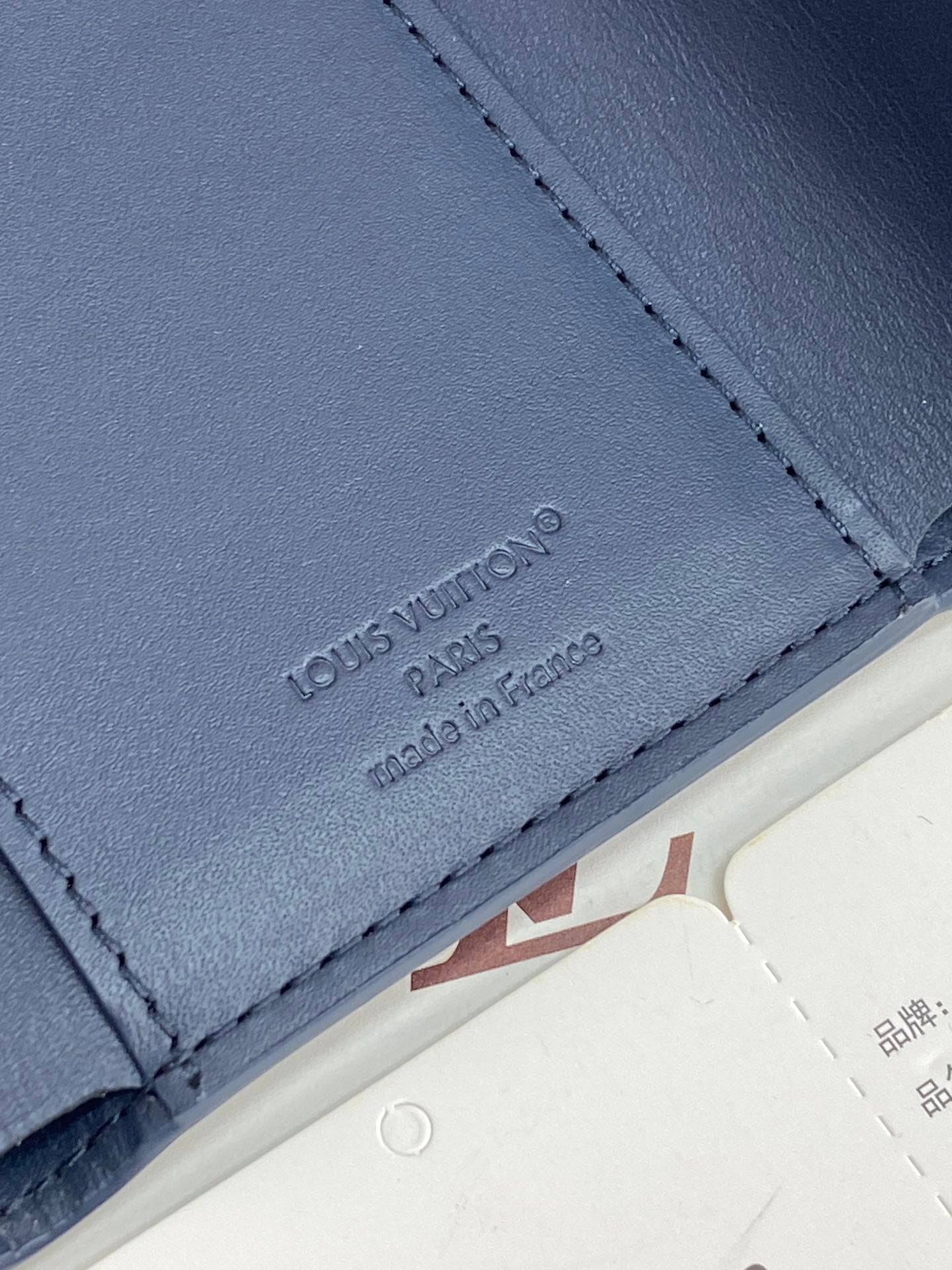 Blue leather card holder panel with 'Louis Vuitton Paris' embossing, stitched