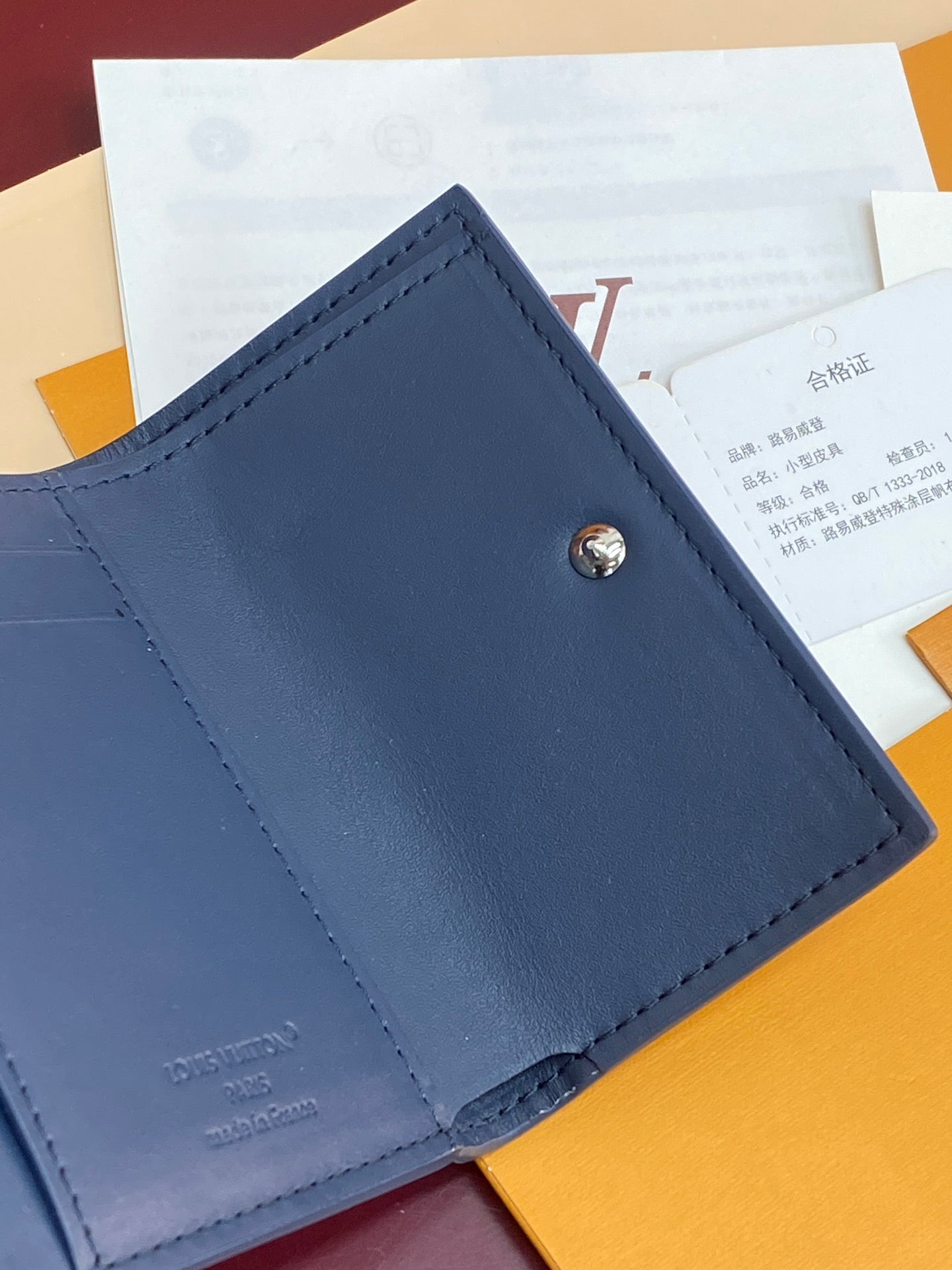 Blue leather card holder with stitched edge and round metal snap button