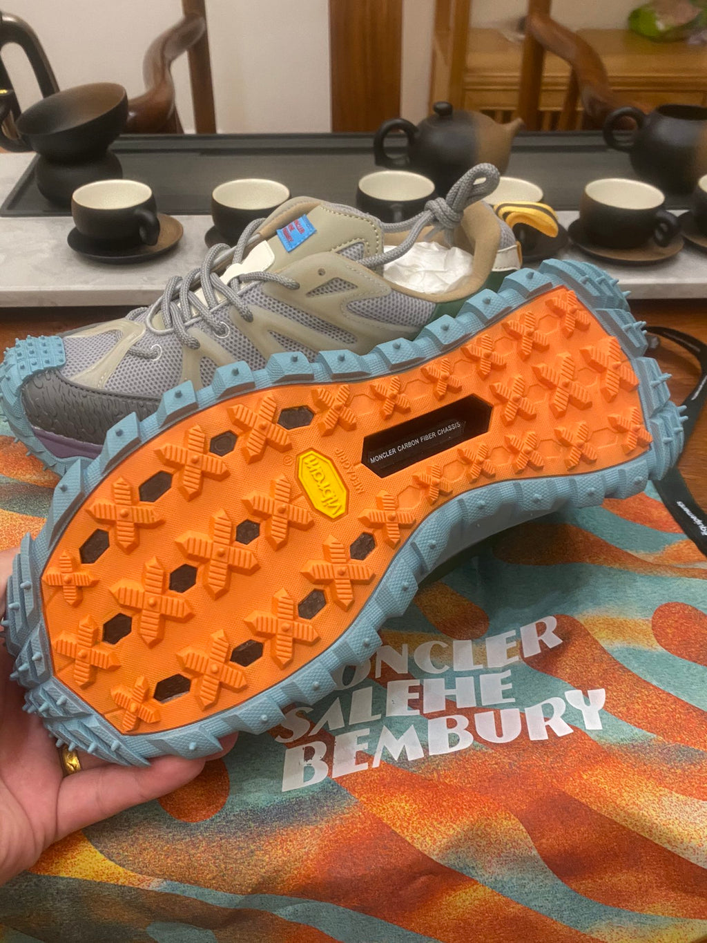 Sneaker outsole view: light blue tread with orange grip, textured lugs and gray upper