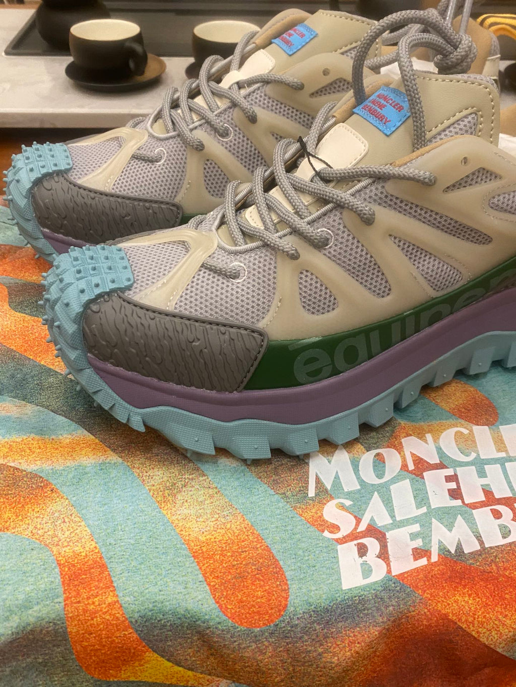Light gray sneakers with olive strap details and turquoise treaded outsole, side view