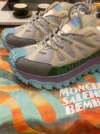 Light gray sneakers with olive strap details and turquoise treaded outsole, side view