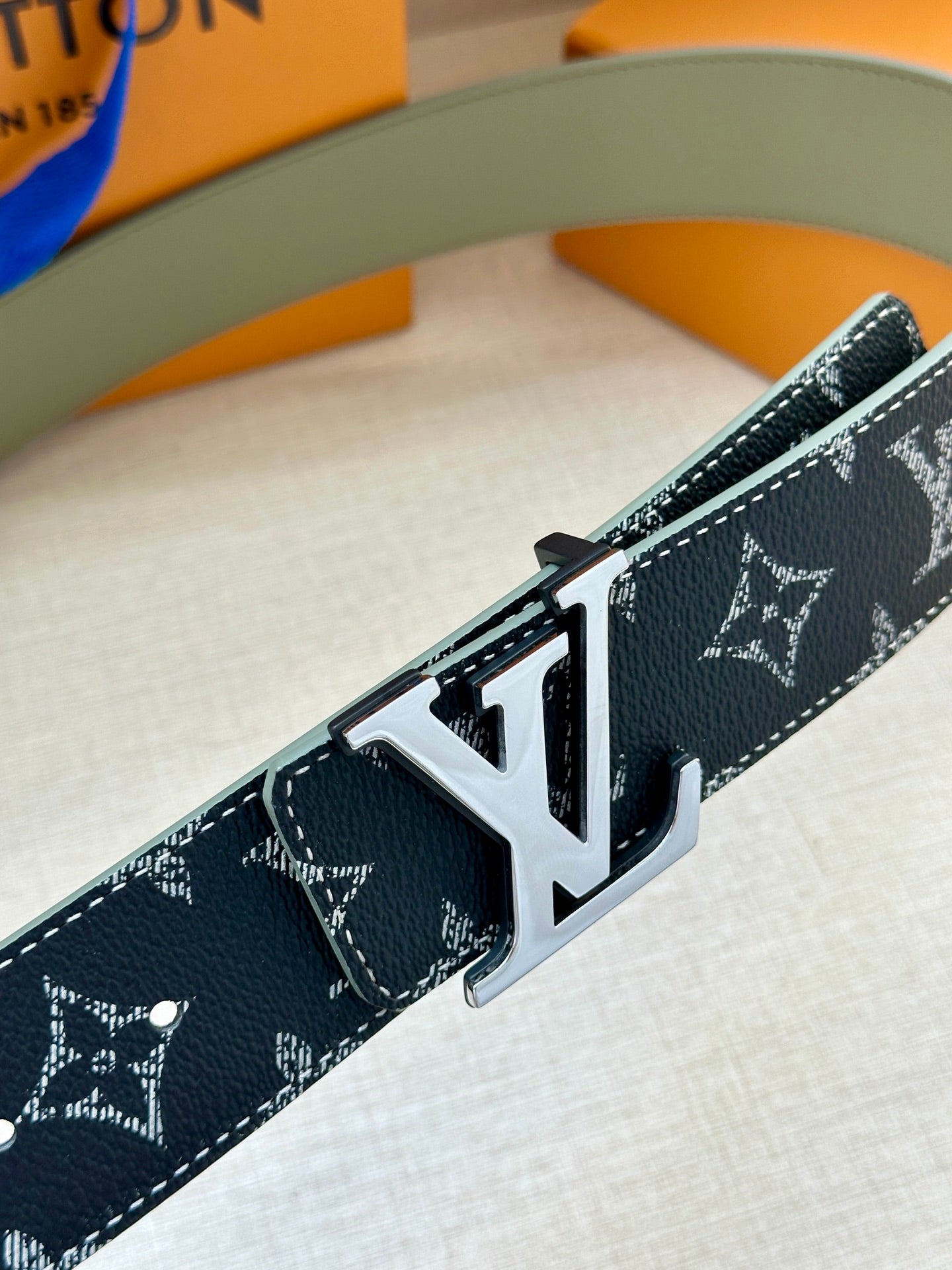 Louis Vuitton belt close-up: navy monogram canvas with silver LV buckle