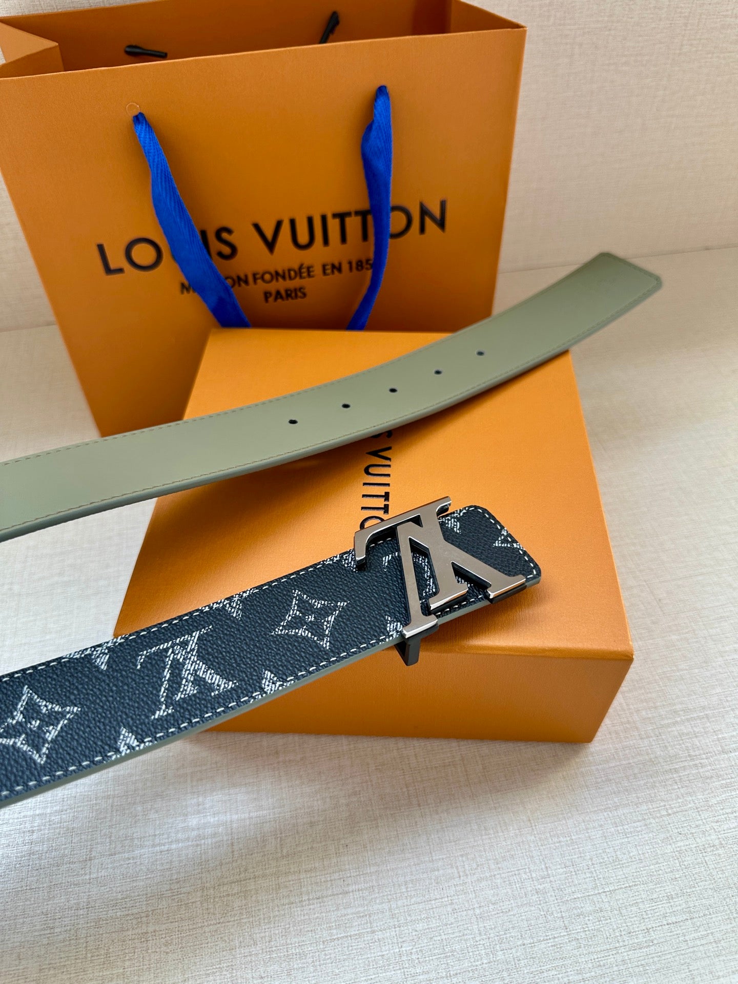 Louis Vuitton belt with navy monogram strap, silver LV buckle, and light-green edge