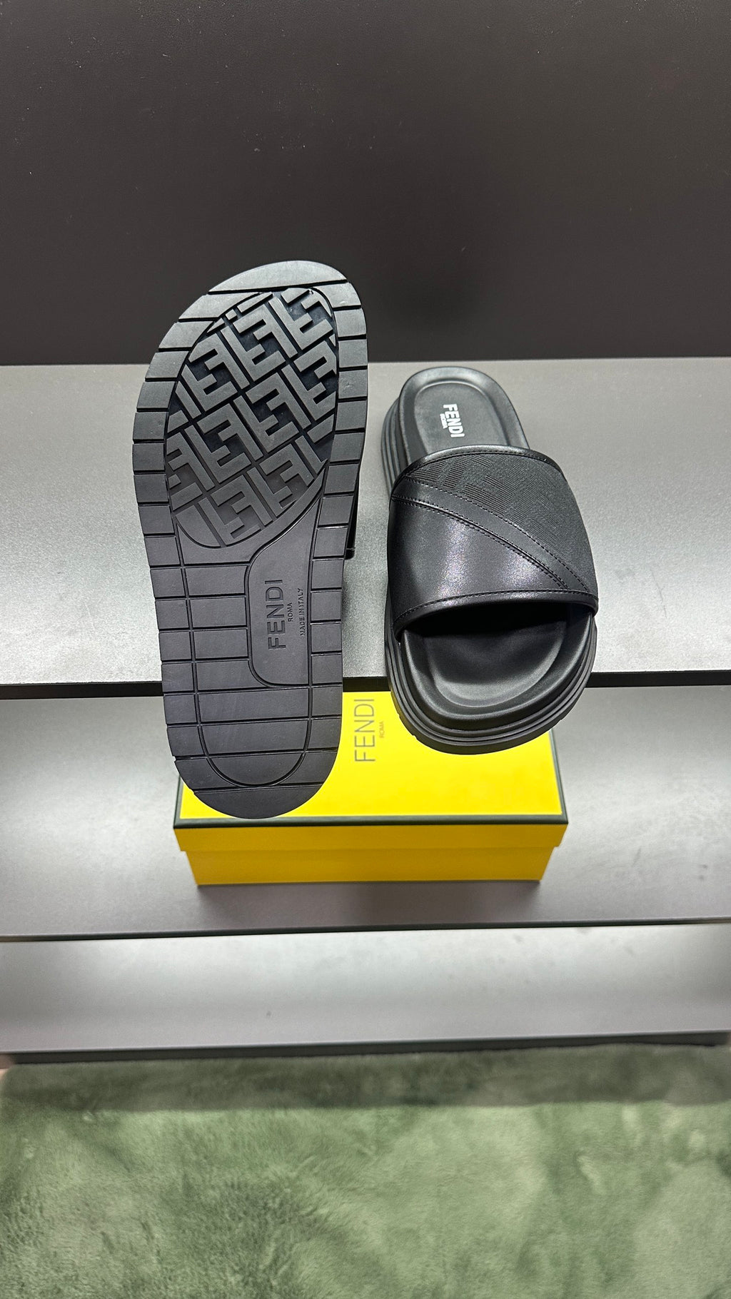 Fendi slide sandals with treaded outsole and dark strap, paired on box