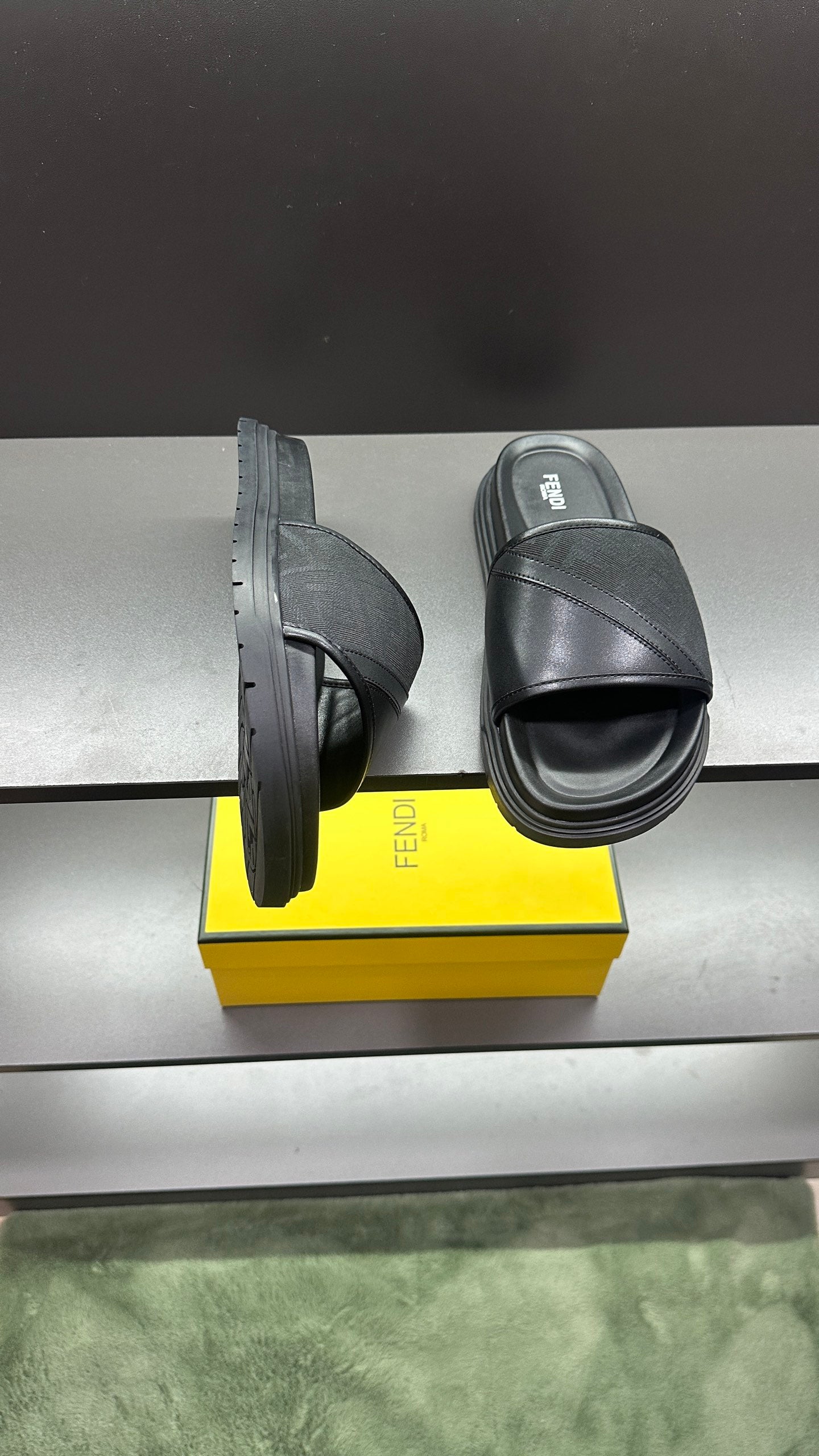 Fendi slide sandals shown from side, dark upper with wide strap over platform sole