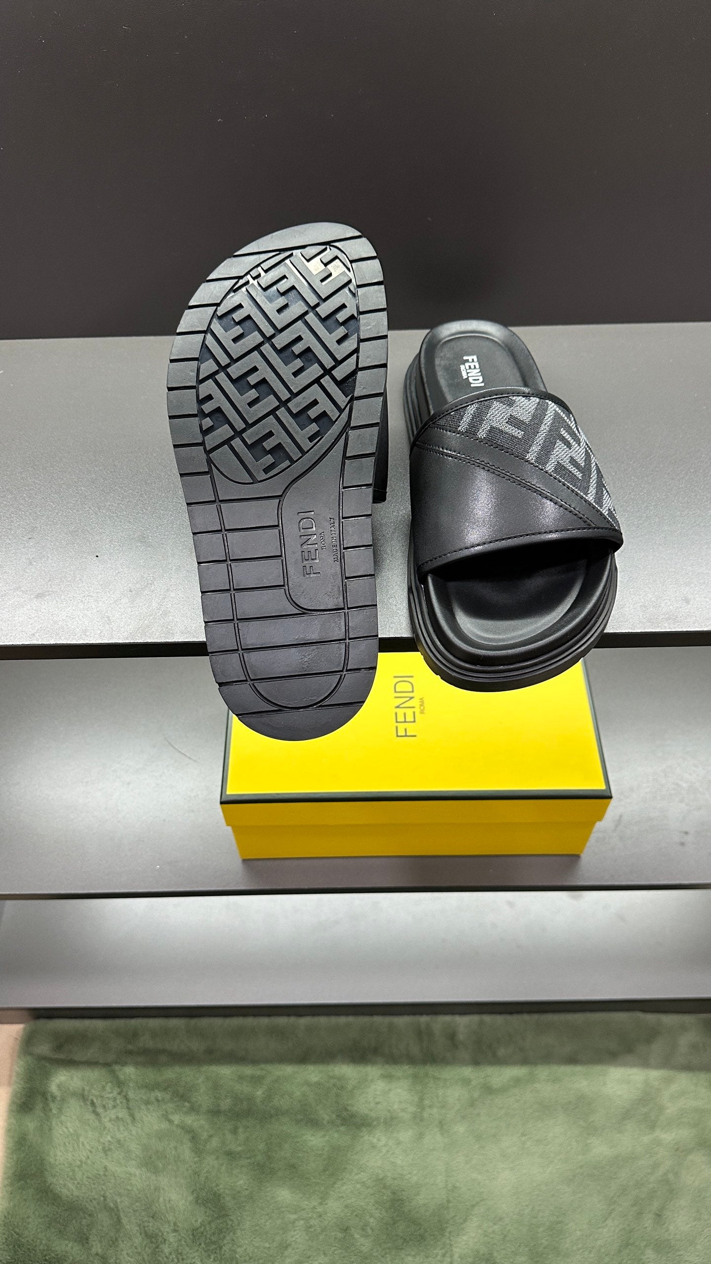 Bottom view of dark slide sandals with FF logo on outsole