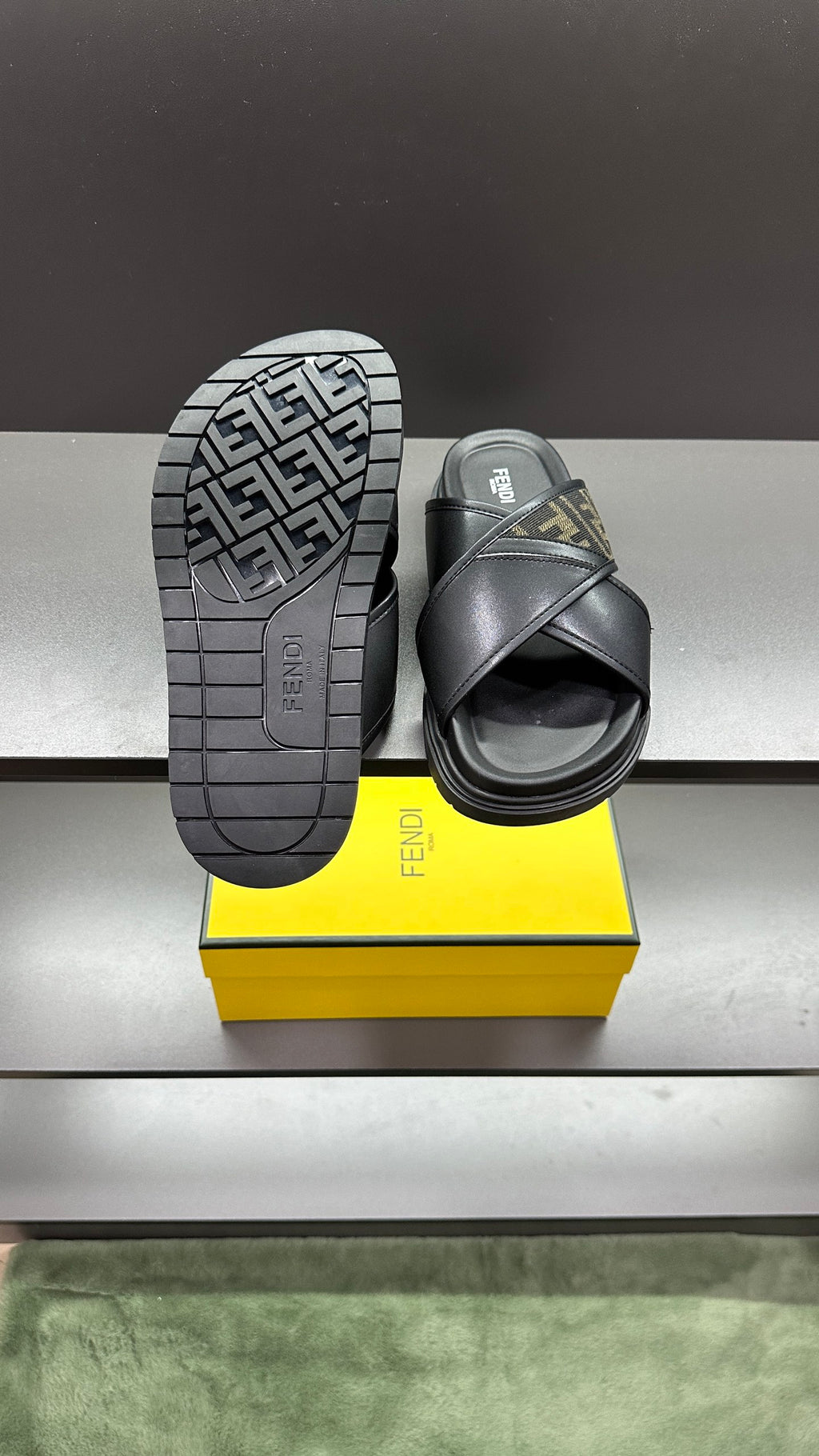 Fendi black slide sandals with treaded outsole facing camera, FF logo strap