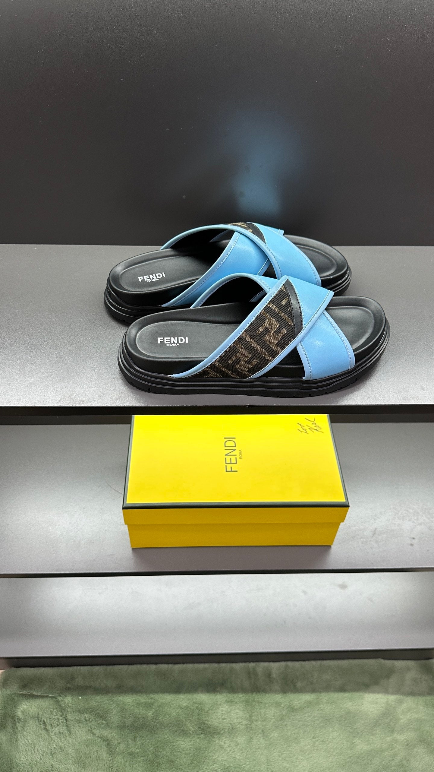 Fendi blue slide sandals with cross straps and dark rubber footbed, shown from side