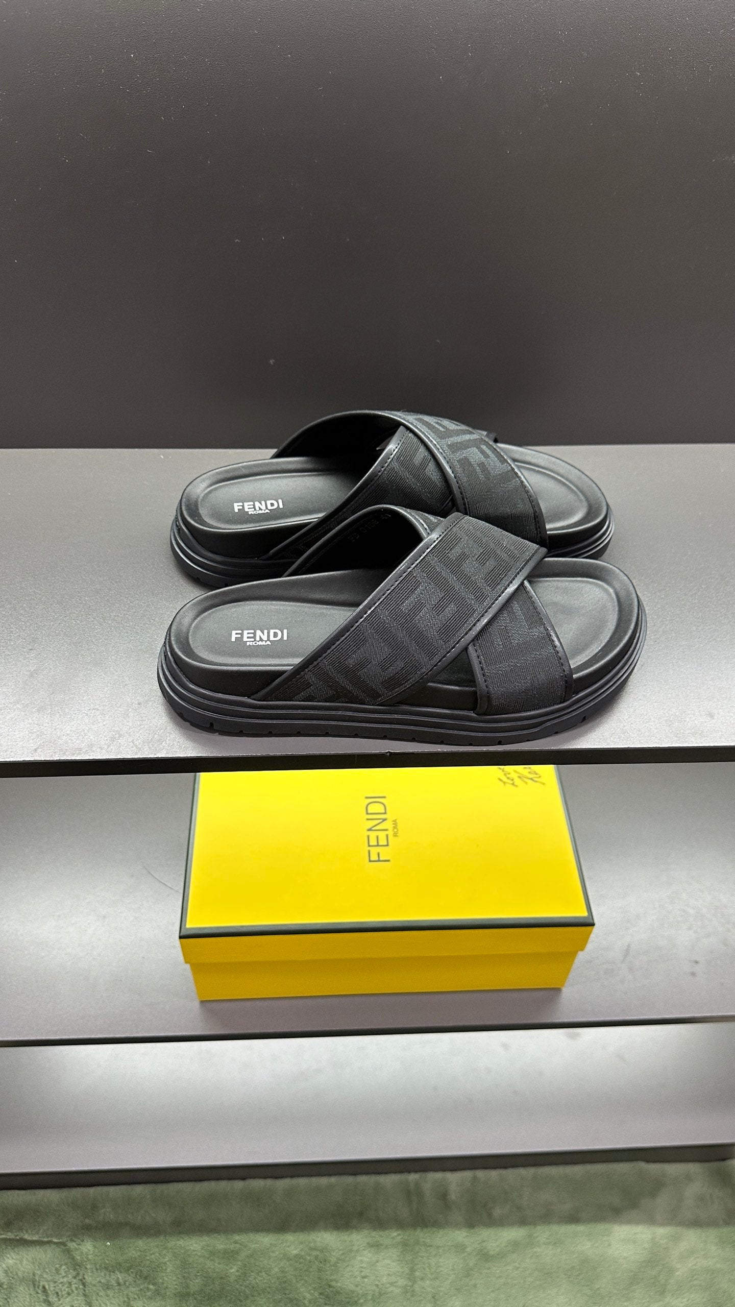 Fendi slide sandals, side view of dark straps with FF logo print on padded footbeds