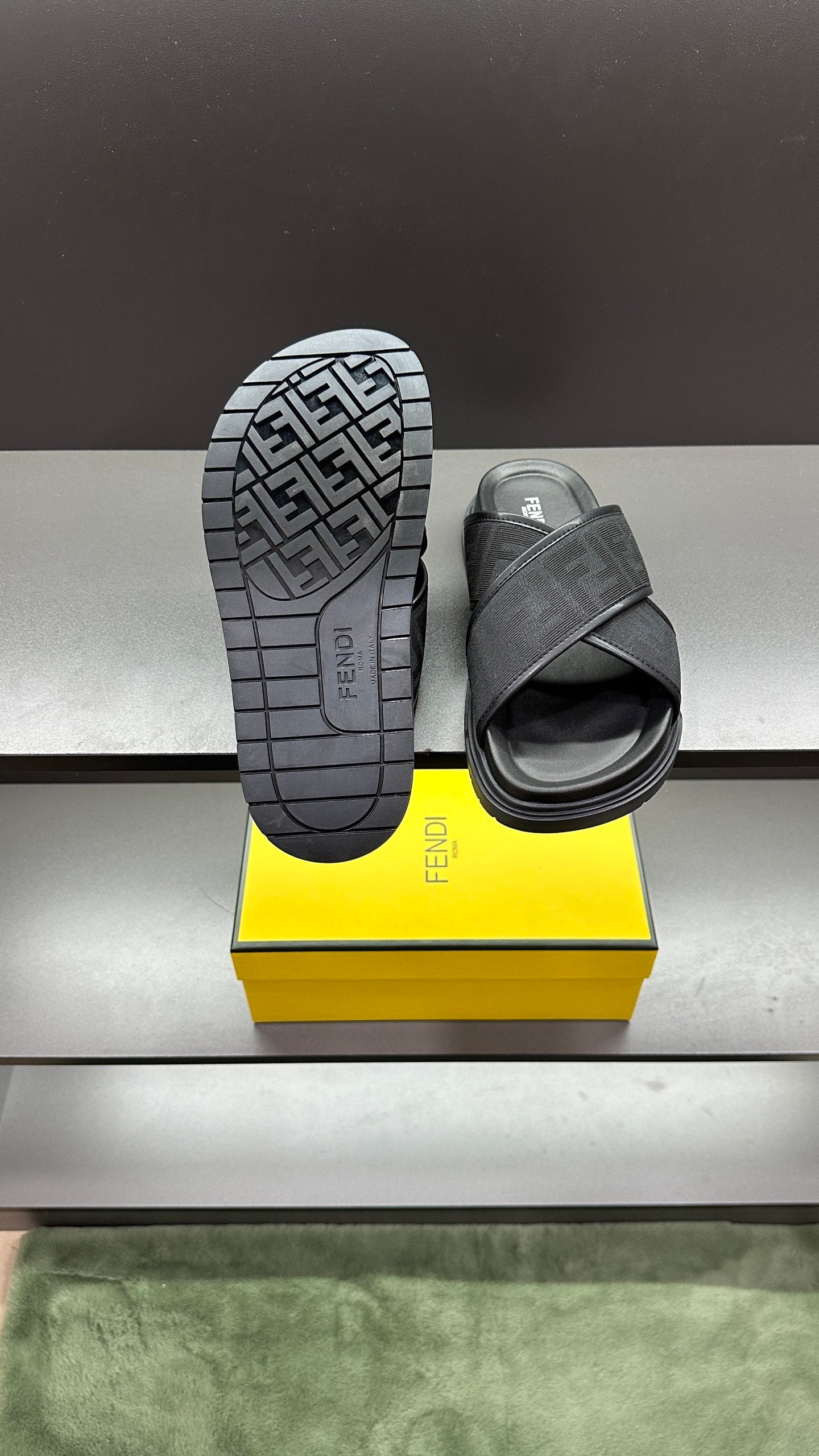 Fendi slide sandals, one outsole facing camera with FF tread pattern and dark strap