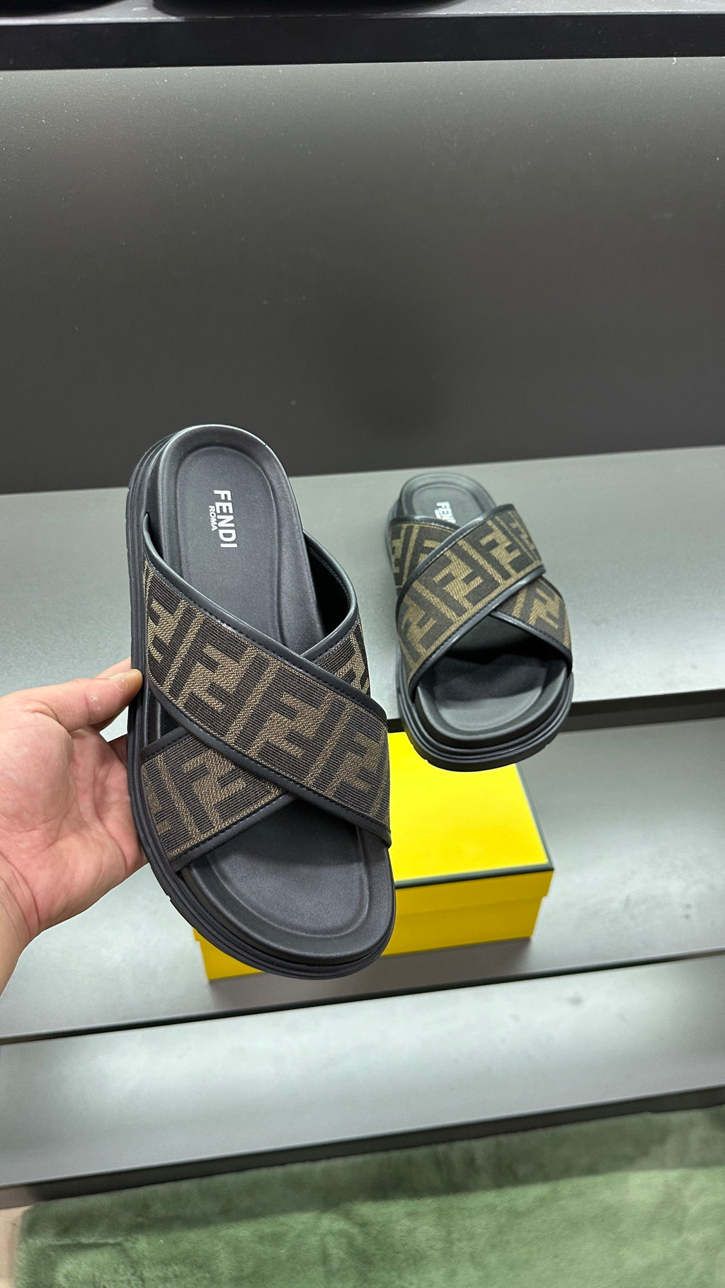 Fendi slide sandals held up, FF logo strap with dark rubber sole and footbed