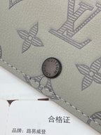 Small bag close-up of snap button and monogram pattern with stitched edge.