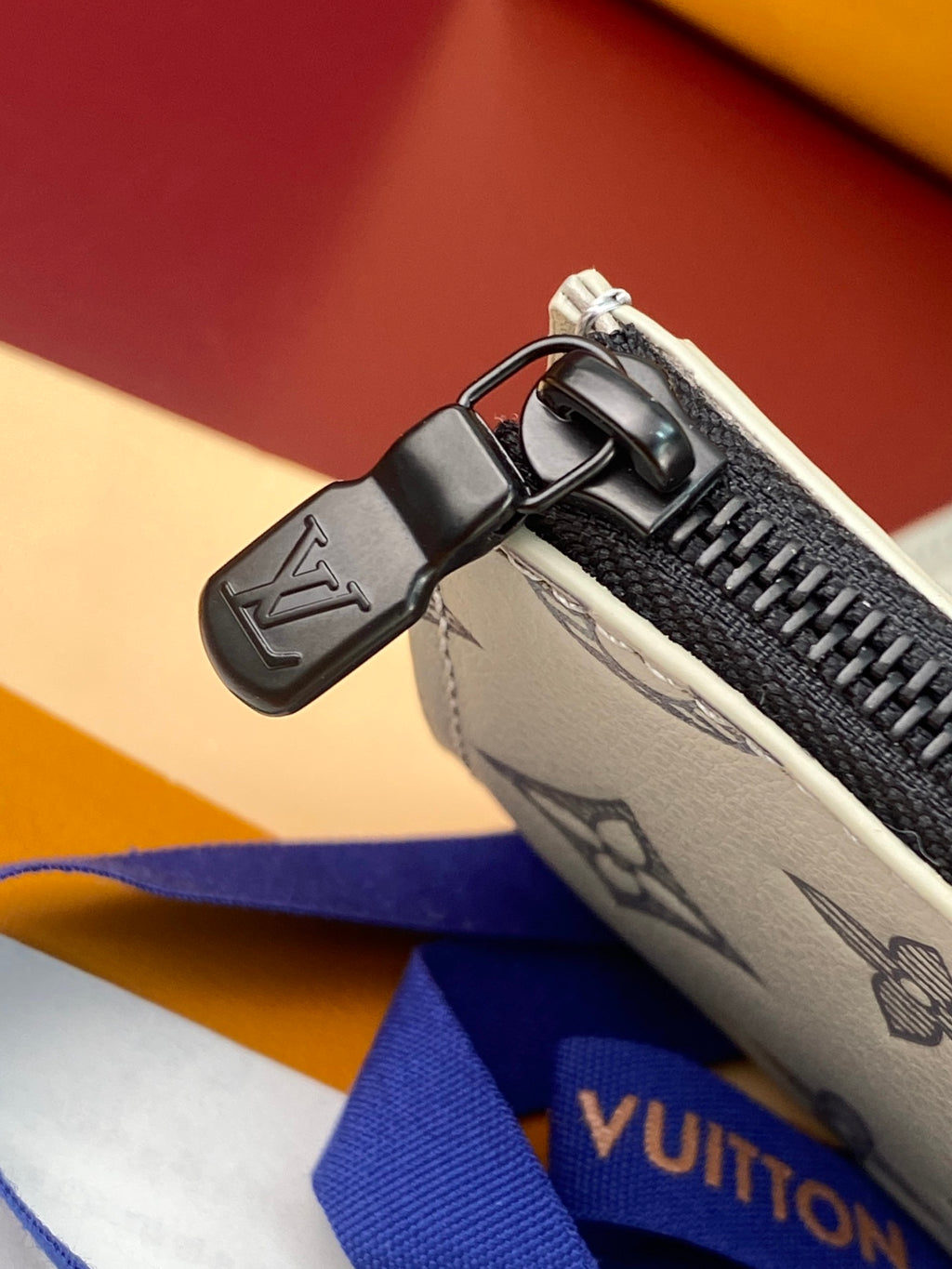 Small bag zipper pull and strap hardware on gray monogram canvas.