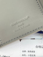 Small bag close-up of embossed "Louis Vuitton" logo on light gray leather.