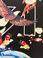 Black T-shirt close-up: winged bird figure with confetti shapes graphic